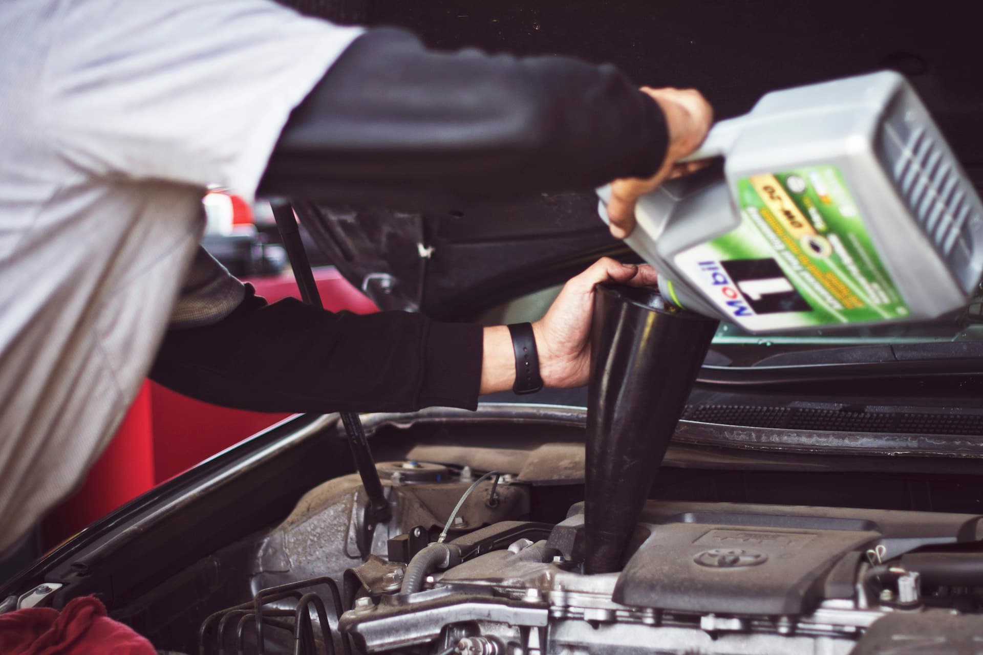 Mechanic pouring oil during a service at the shop